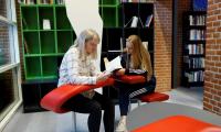 To piger sidder og læser i en rød stol i Studiecentret