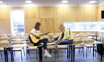 To piger spiller guitar på et bord i Musikhuset