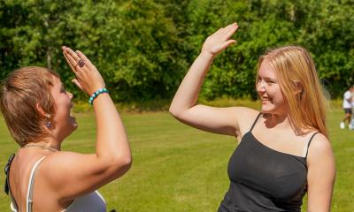 To glade 1.g-piger giver hinanden high five på den græsgrønne boldbane